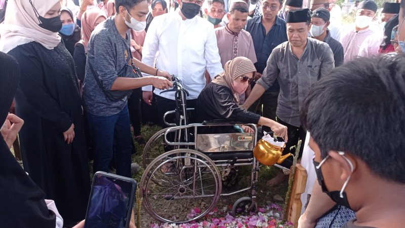 Istri mendiang Ikhsan Kalbi, Erna mengantar jenazah sang suami ke pemakaman menggunakan kursi roda, Sabtu (19/2/2022)/hariansulteng