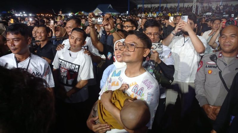 Momen Abdul Karim Aljufri gendong bayi warga saat nonton Dewa 19 di konser BERAMAL, Senin malam (16/9/2024)/hariansulteng