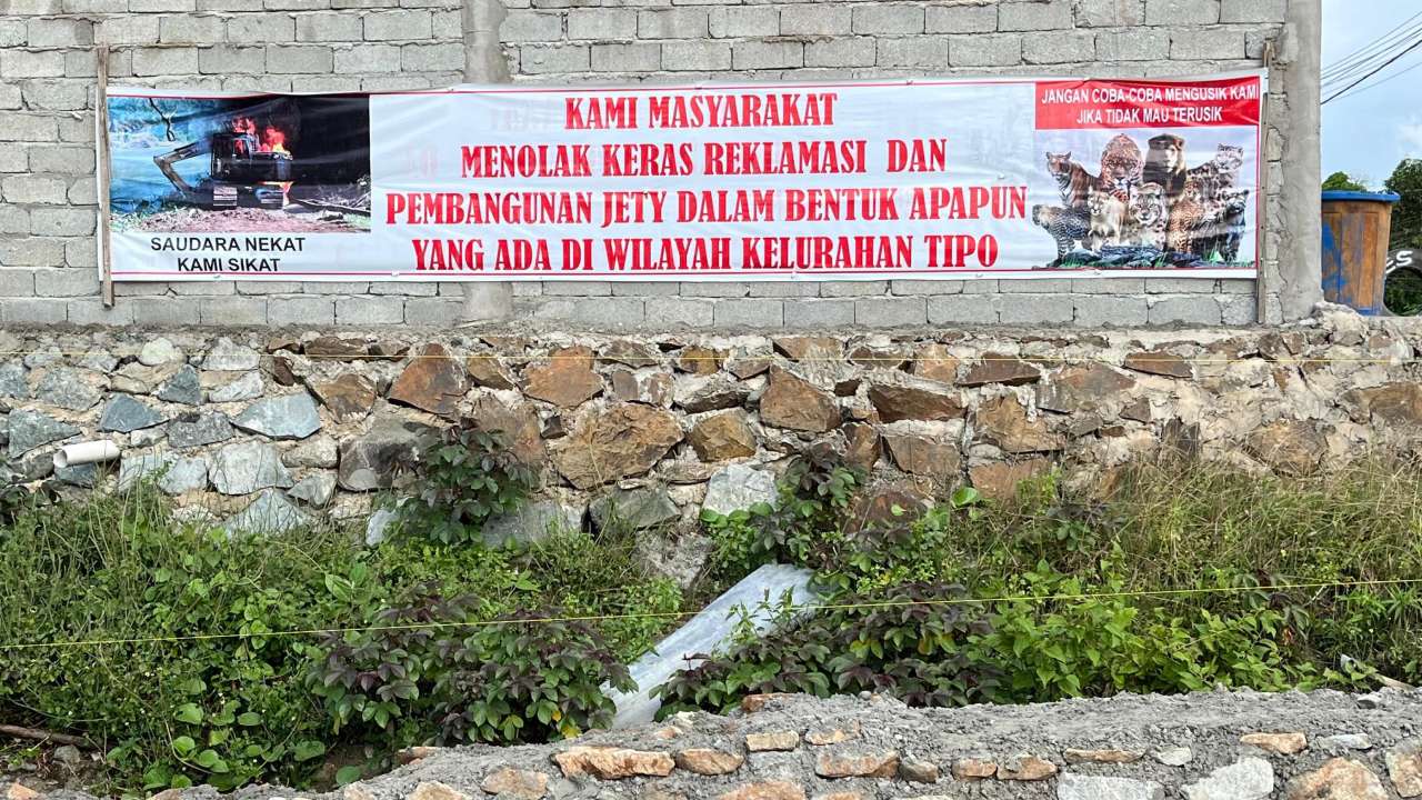 Spanduk penolakan terpampang di dekat jetty PT BAM di Kelurahan Tipo, Kecamatan Ulujadi, Palu (Sumber: Fandy/hariansulteng.com)